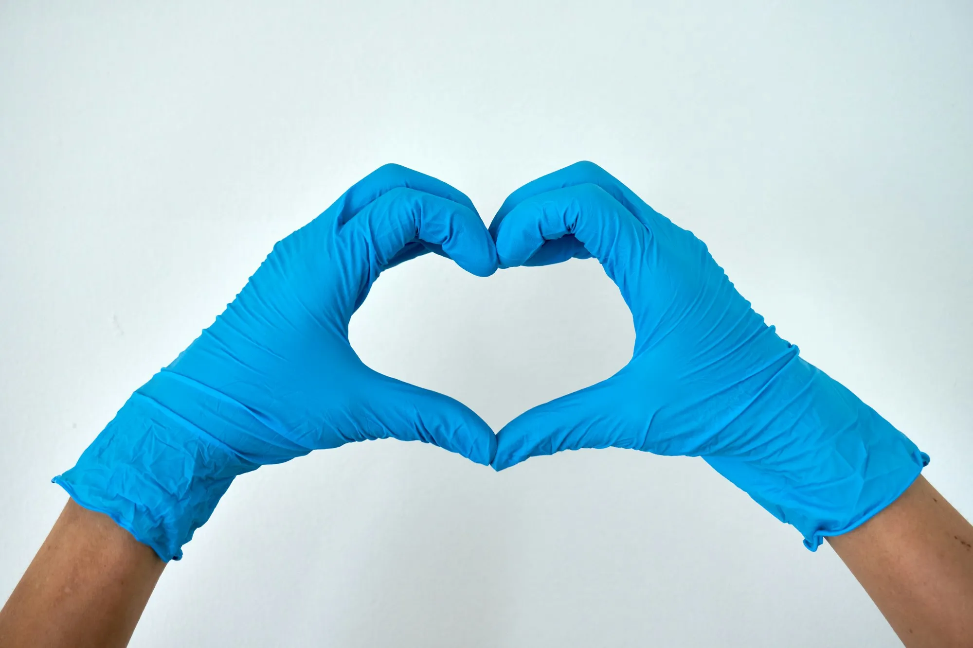 Two hands in blue cleaning gloves making a heart shape